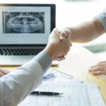 midsection doctor giving handshake patient while sitting hospital