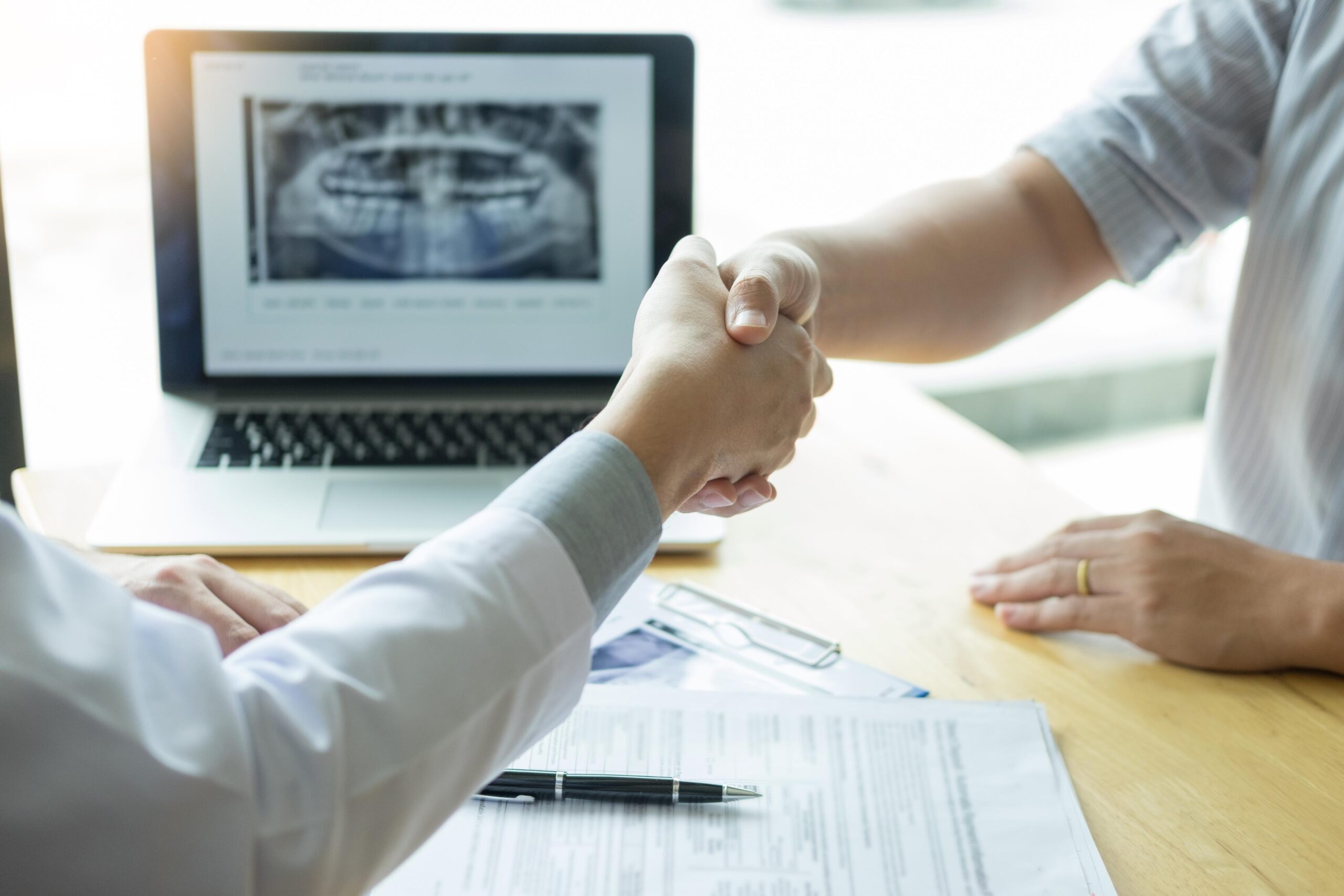 midsection doctor giving handshake patient while sitting hospital